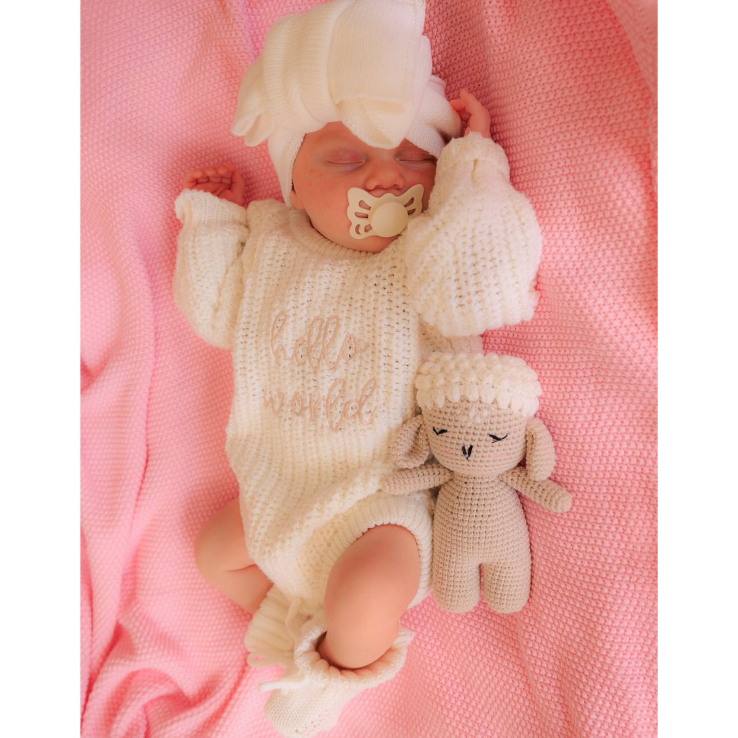 Hello world announcement romper. Pink knit blanket. White knit booties and bow
